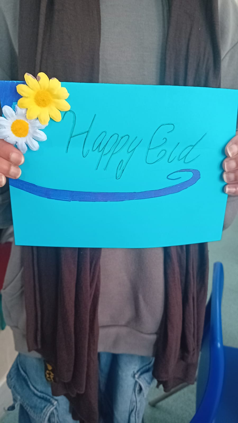 A child holding a handmade Happy Eid card