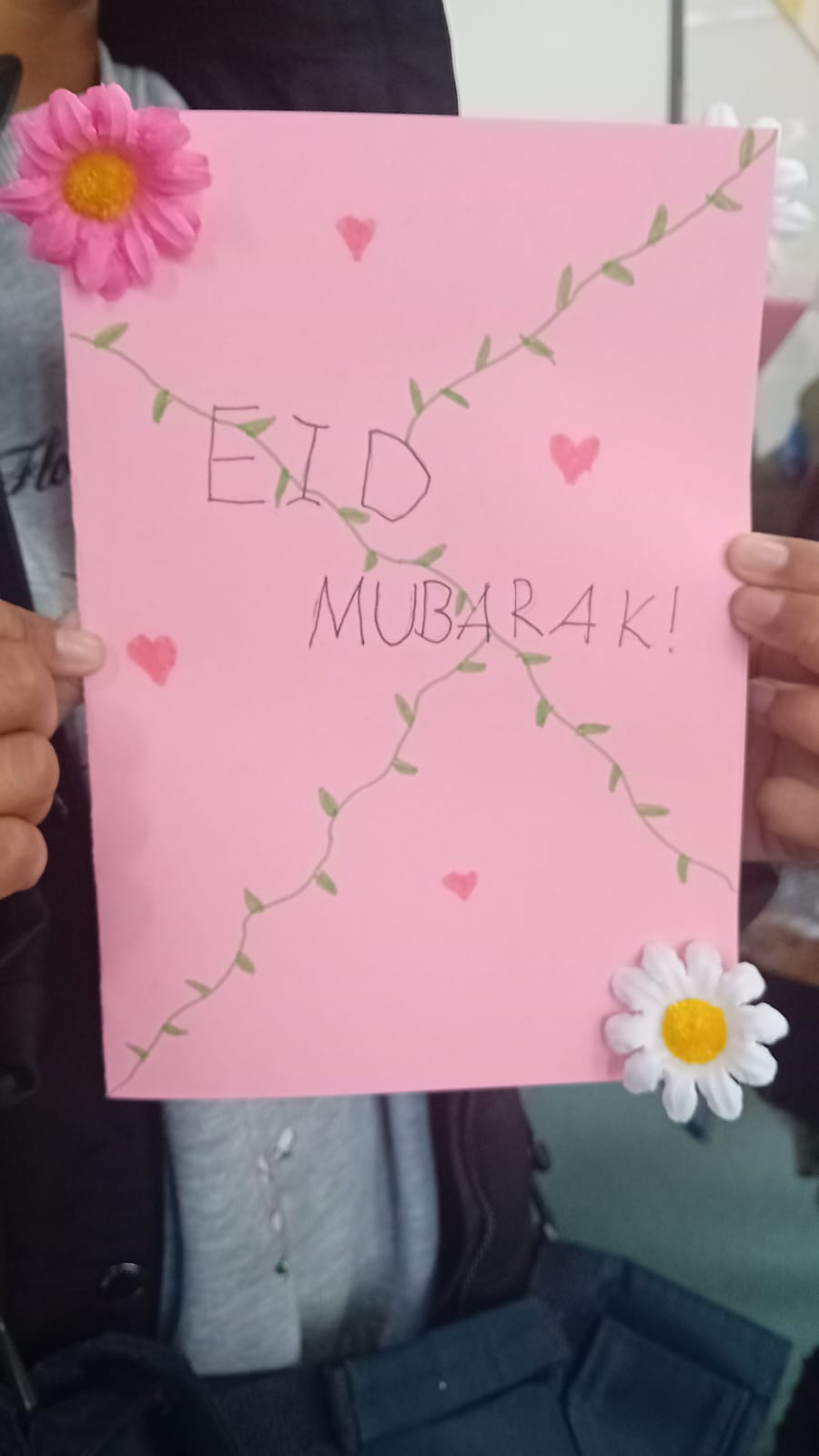 A pupil holding a handmade Eid Mubarak card